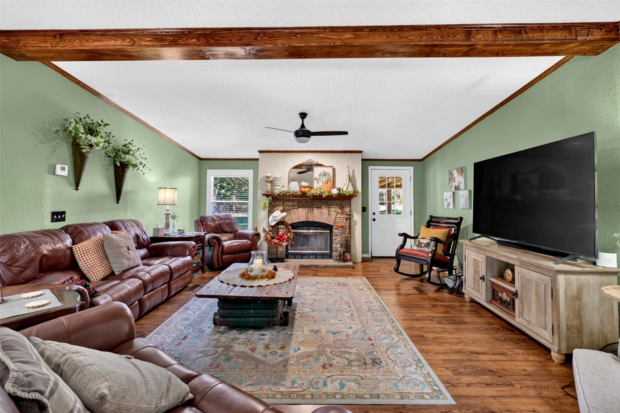 Spacious Living area featuring stone fireplace, ceiling fans and windows for natural light.