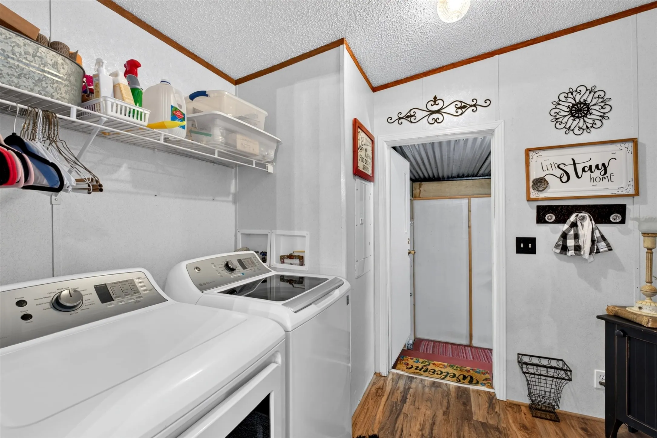 Laundry area with durable wood-finish flooring, wire shelving, and overhead lighting