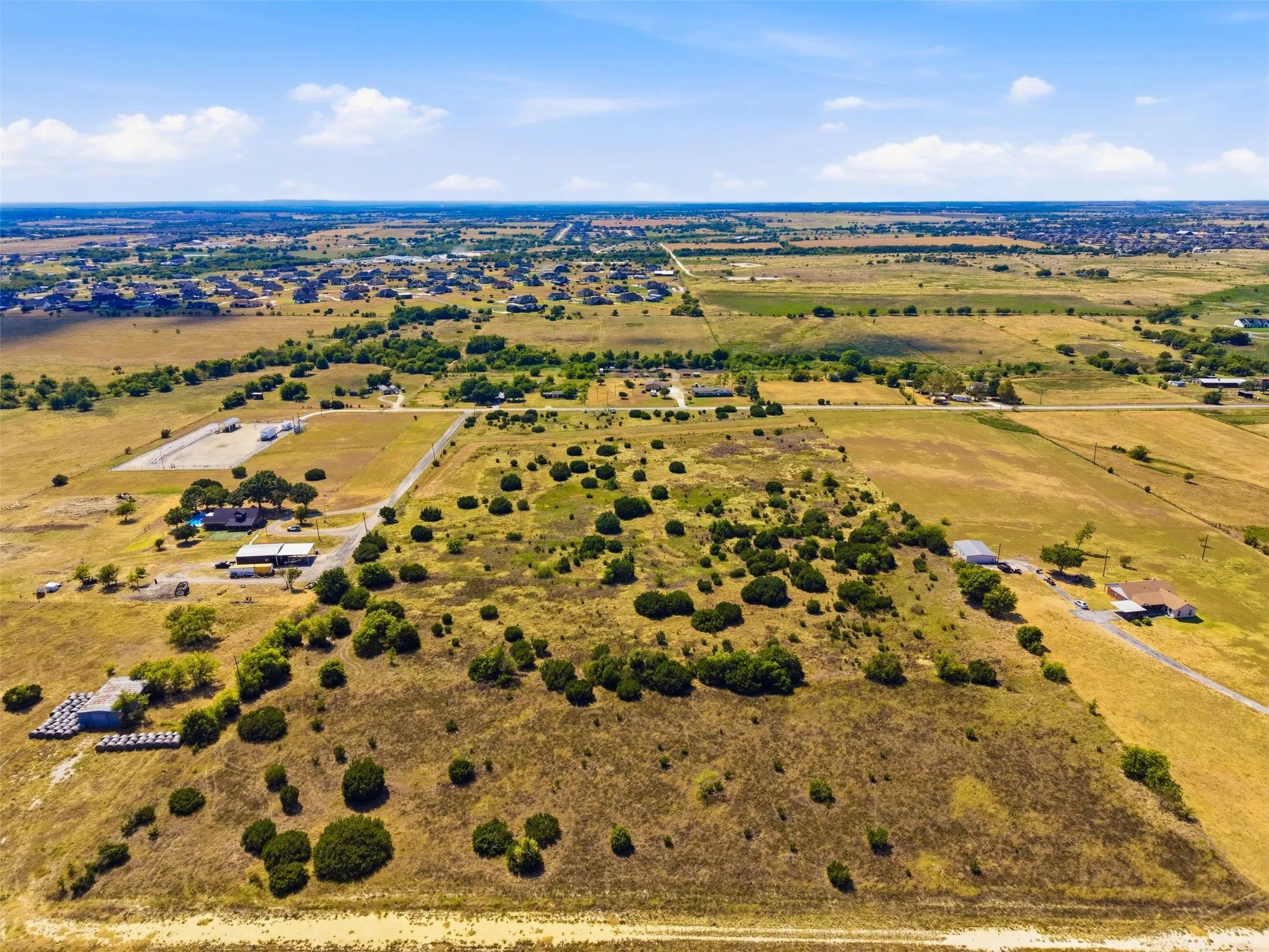 Expansive land parcel with significant road frontage, featuring mature trees and open fields