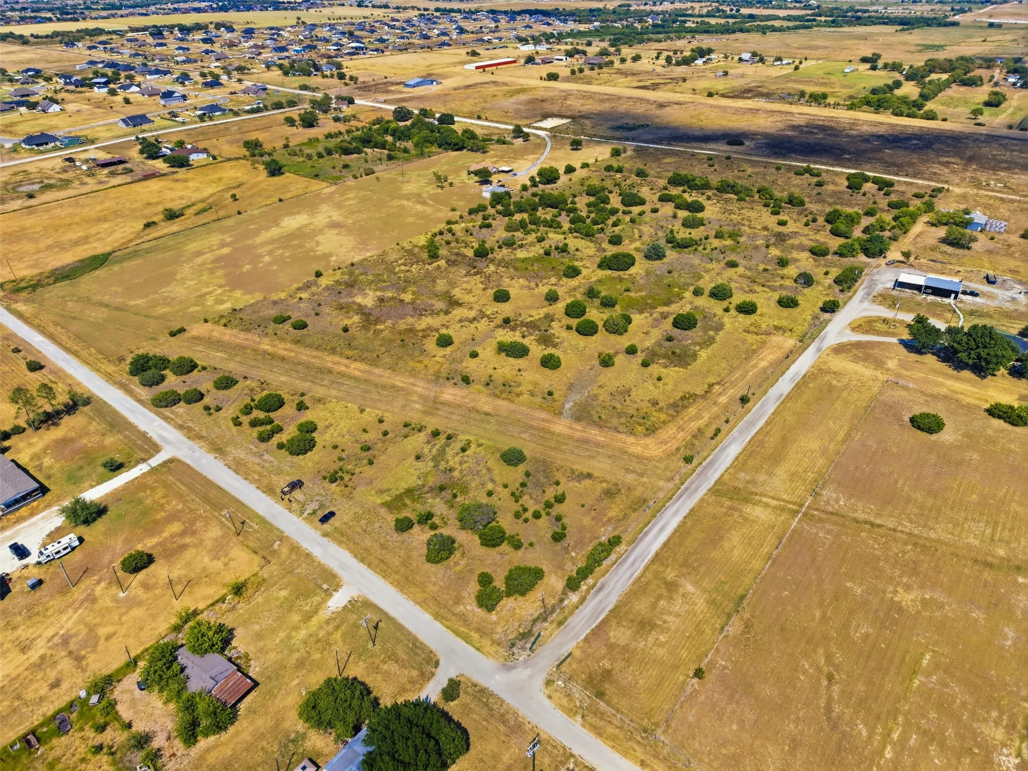 Expansive undeveloped land featuring natural foliage and a dirt road entrance