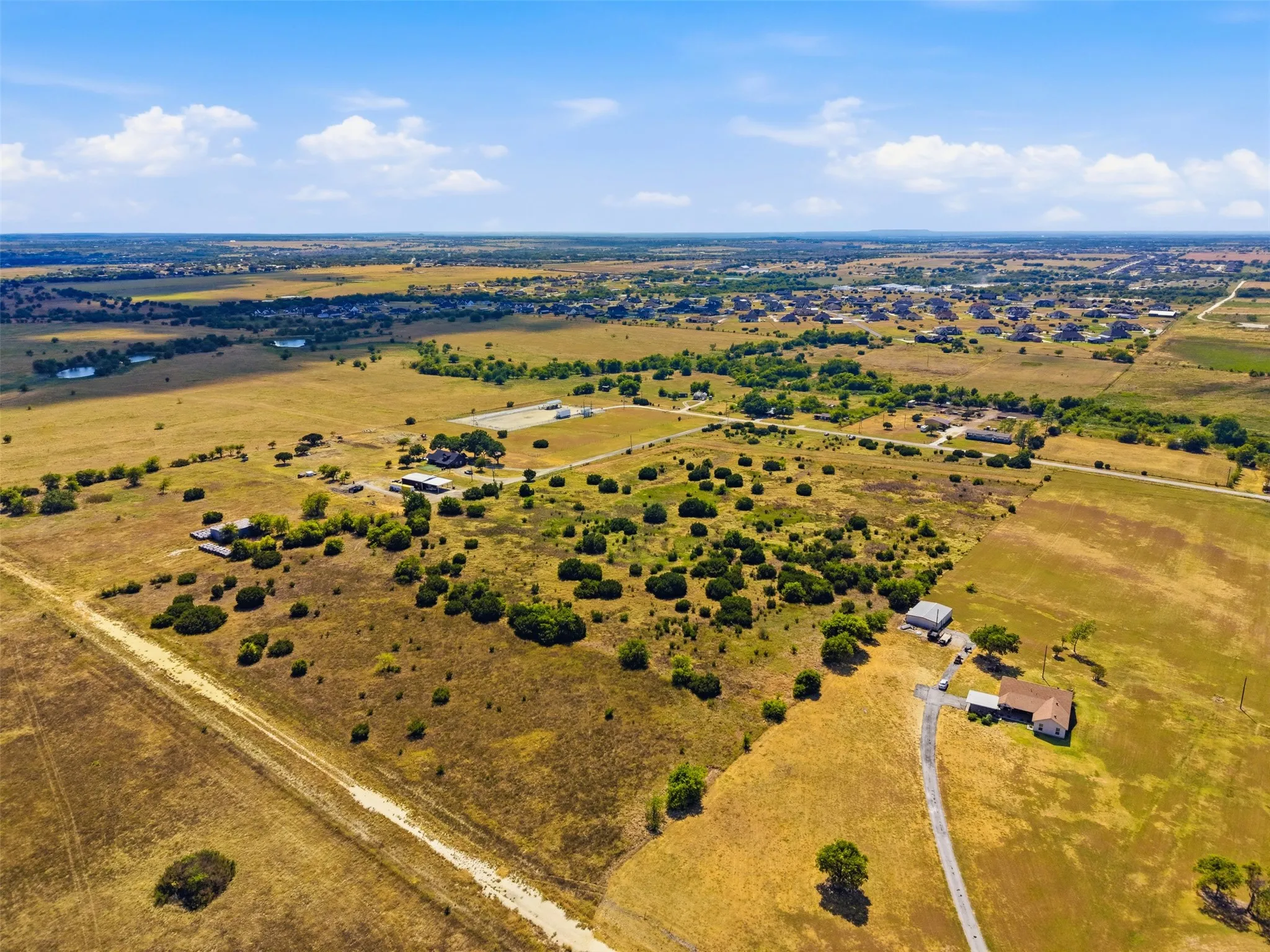 Expansive rural landscape featuring multiple structures, mature trees, and natural vegetation