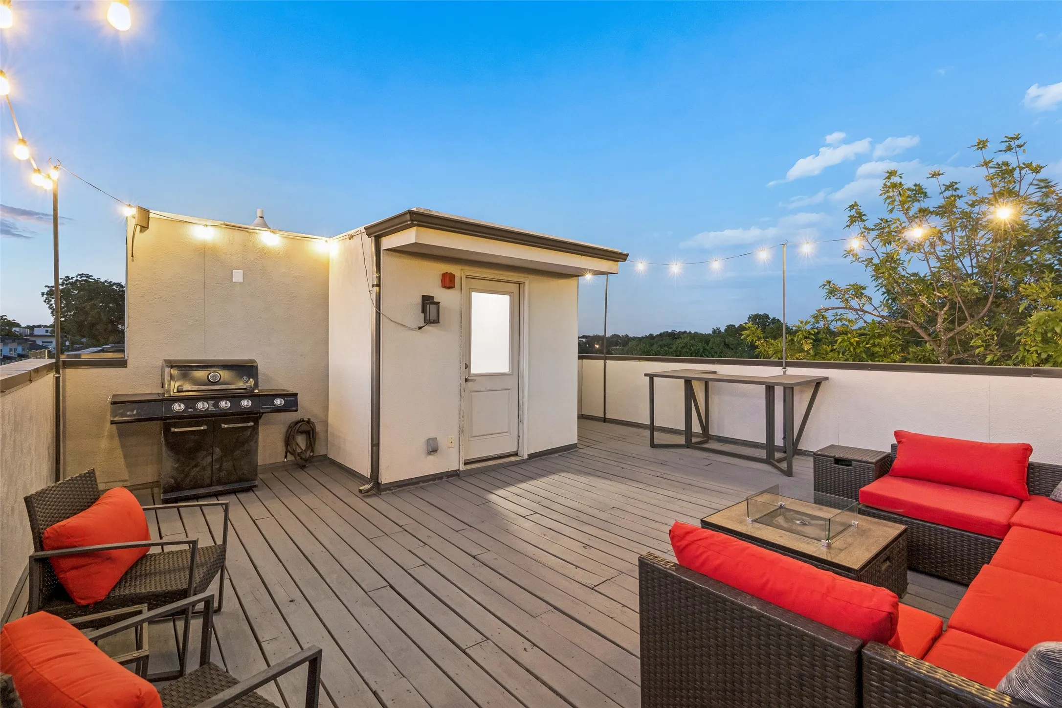 Spacious rooftop deck featuring wood-finish flooring, string lighting, and perimeter walls