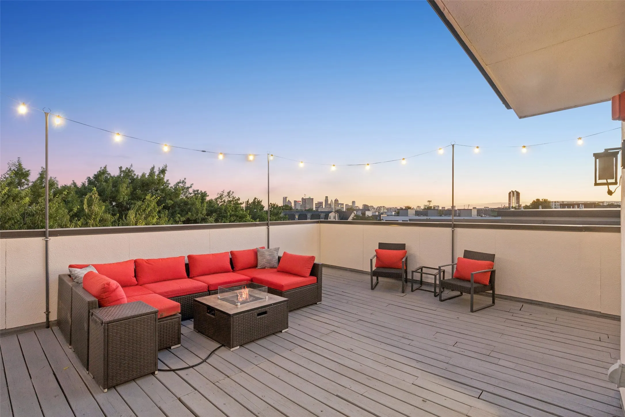 Rooftop deck featuring plank flooring, string lighting, and a city skyline backdrop