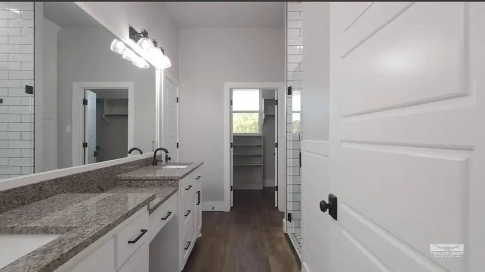 The main-level primary suite is a standout: a spacious 15x16 retreat with a spa-style bath featuring a full-length walk-through glass shower with dual shower heads, a double vanity, and a custom closet — plus a rare bonus, a private 8x12 storm shelter concealed behind built-in bookshelves, complete with its own power, A/C, and ventilation.