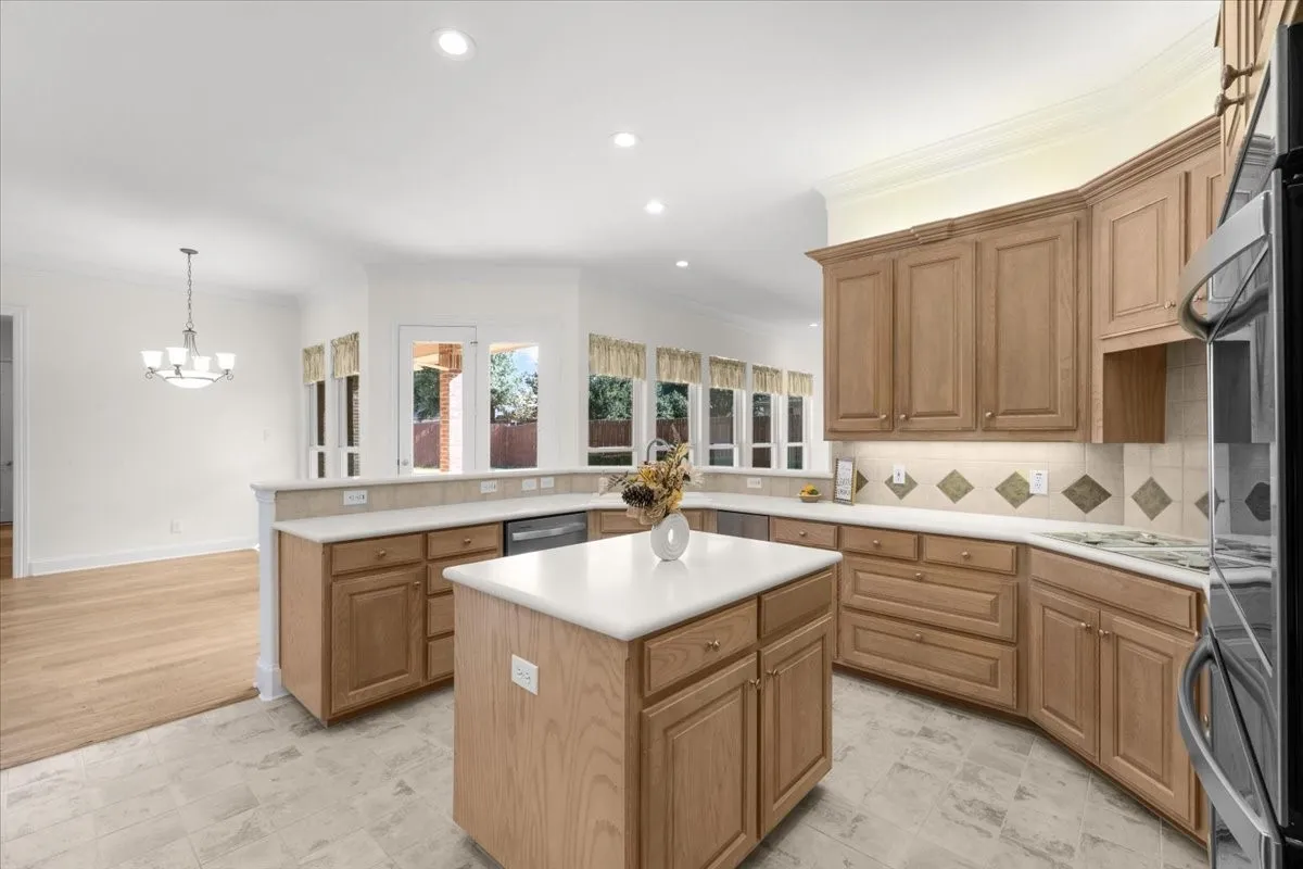 Kitchen featuring light wood cabinetry, white countertops, a central island, recessed lighting, and a tile backsplash with accent tiles