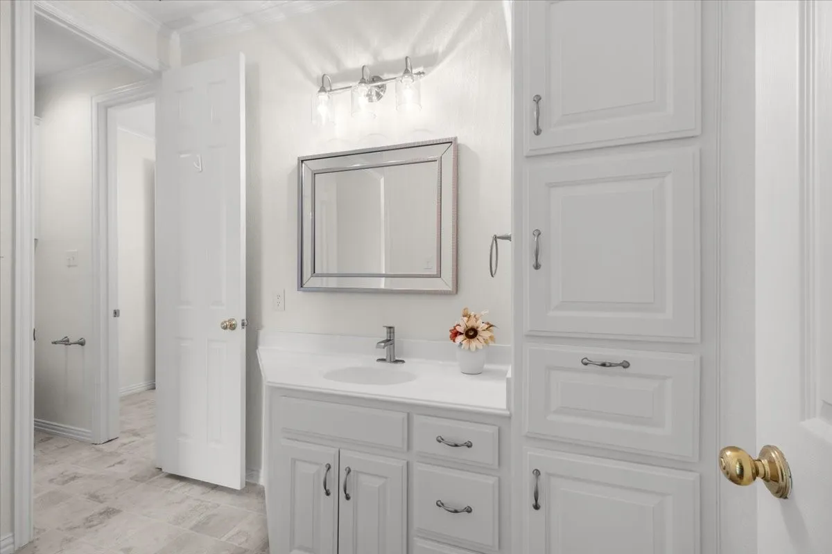 White vanity with a single basin sink, chrome faucet, and framed mirror