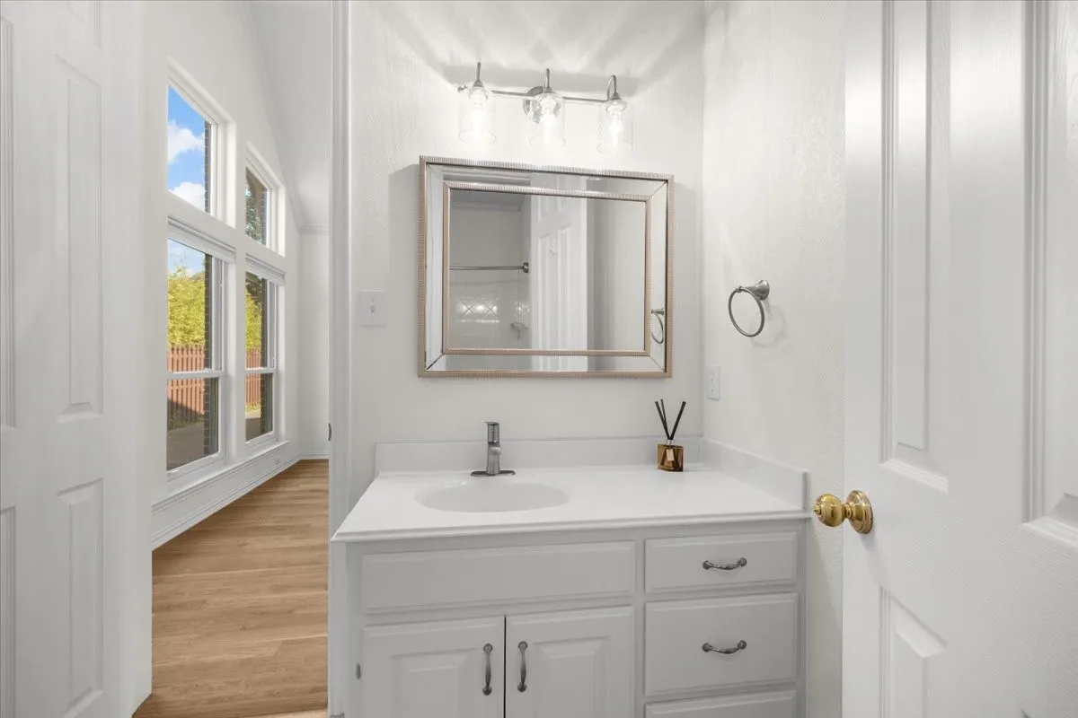 White vanity with an integrated sink, polished chrome faucet, and framed mirror