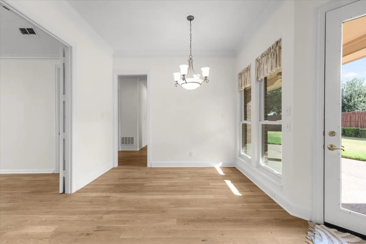 Recessed lighting, wood-finish flooring, white trim, and a multi-light chandelier