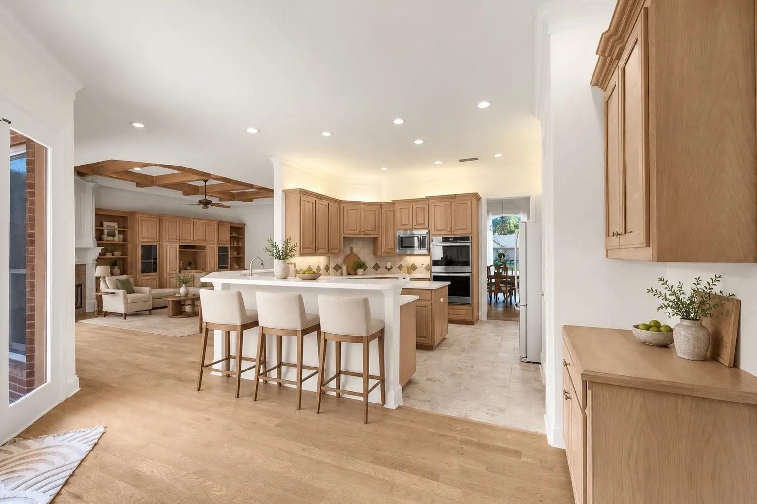 Gourmet kitchen with light wood-finish cabinetry, stainless steel appliances, and a central island with bar seating AI staged