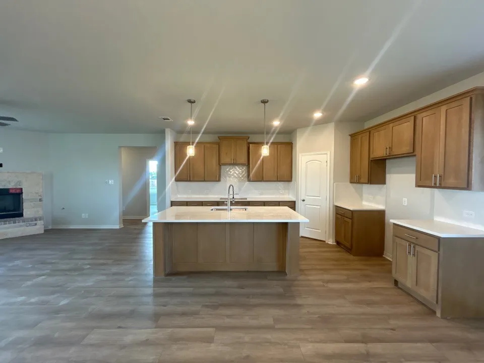 Kitchen featuring a central island with a sink, recessed lighting, pendant lighting, wood-finish flooring, and light-toned cabinetry