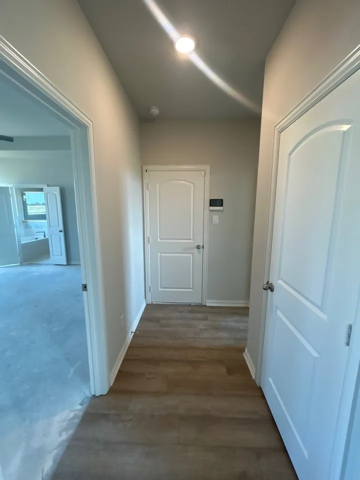 Wood-finish flooring with white trim and paneled doors