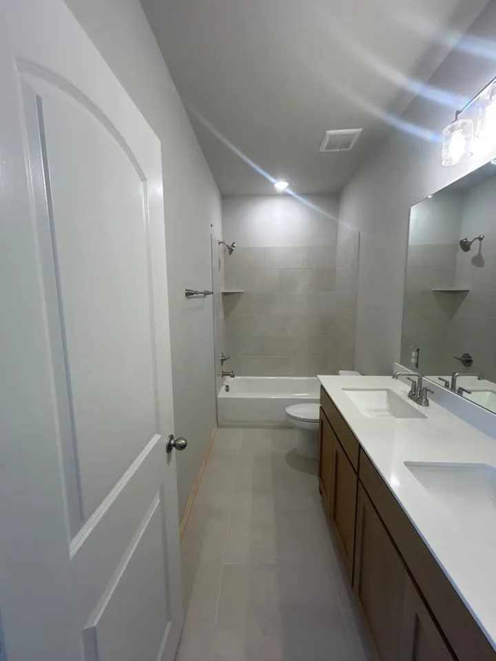 Dual vanity with individual sinks, white countertop, and wood-finish cabinetry
