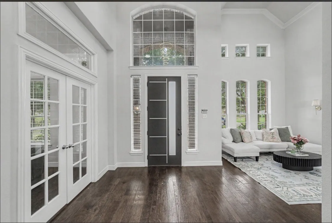 Double French doors with transom window, soaring ceilings, dark wood-finish flooring, and multiple arched windows