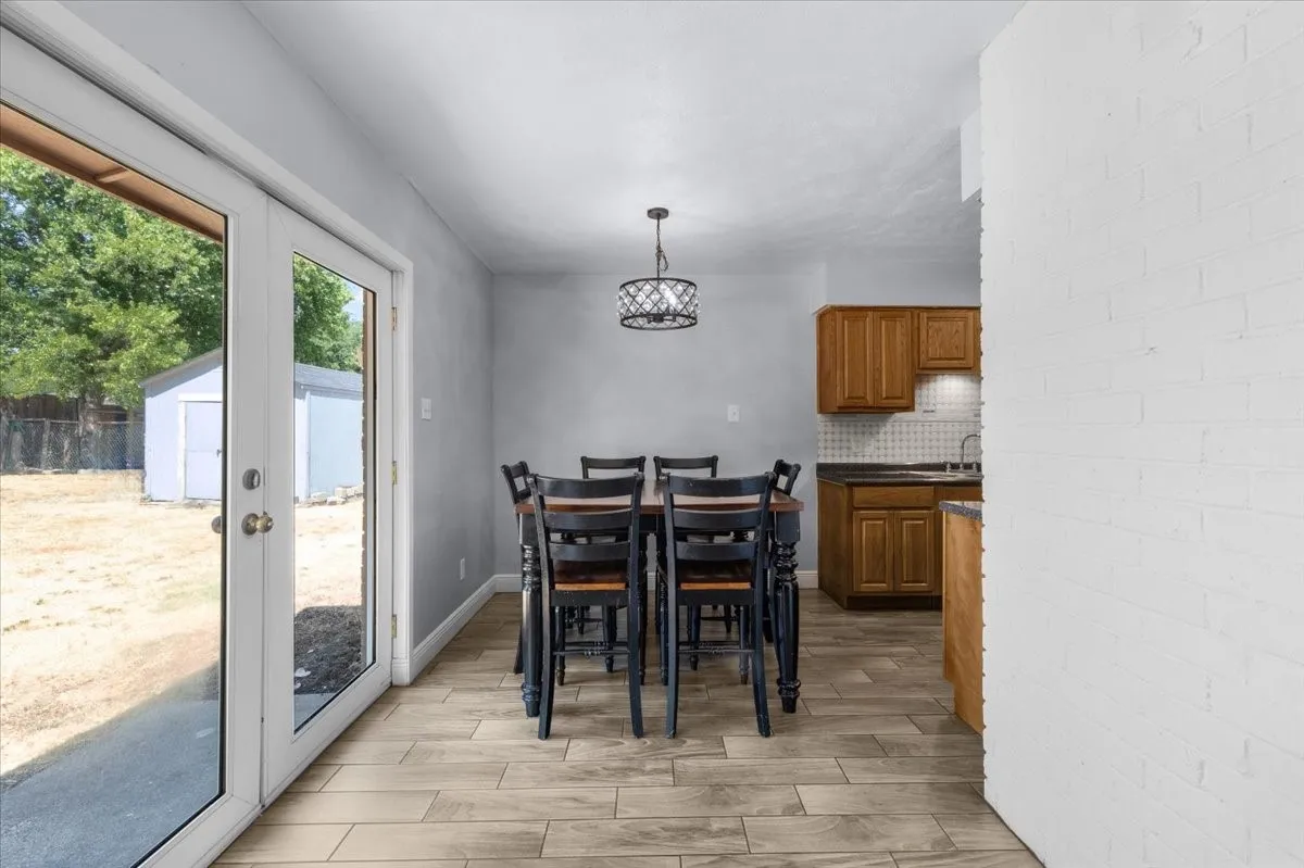 Wood-finish flooring, white double doors, and a decorative overhead light fixture