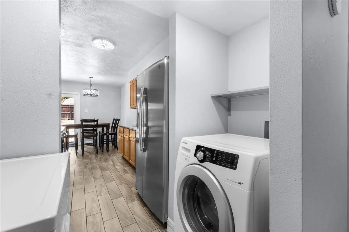 Dedicated laundry area with a wall-mounted shelf, light wood-finish flooring, and natural wood cabinetry