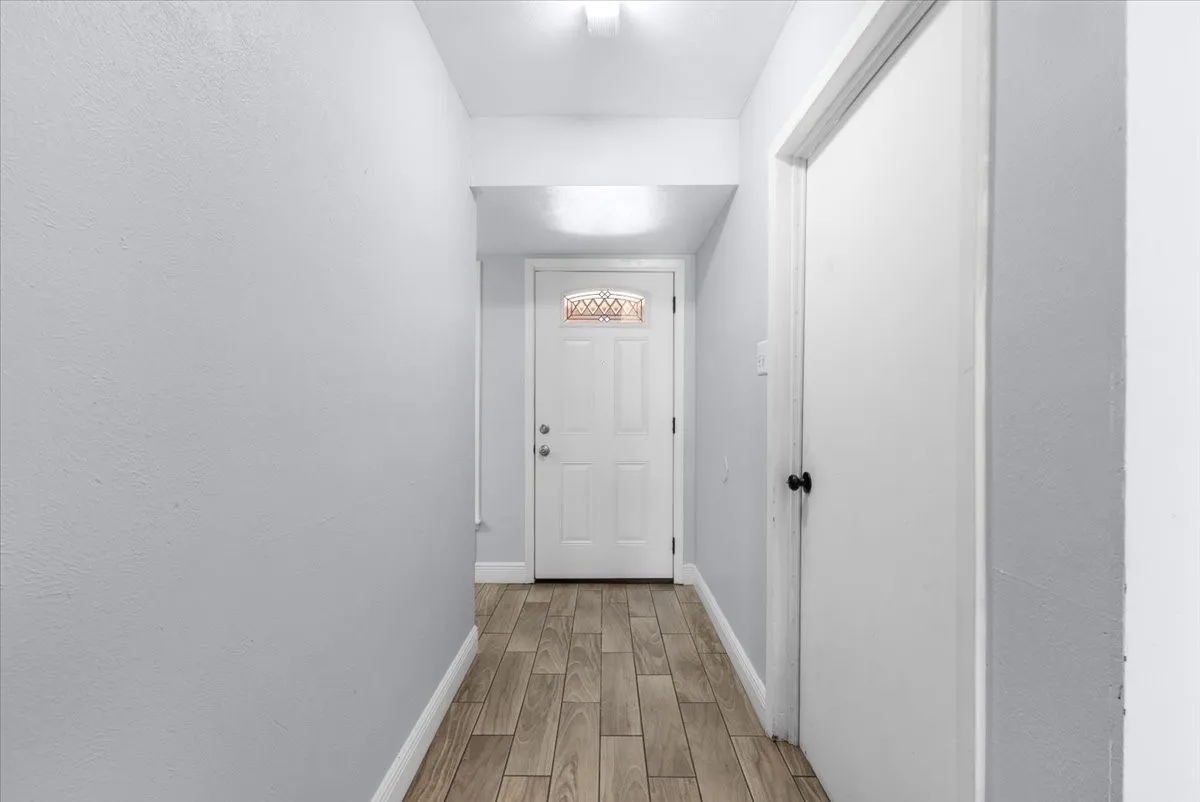 Entryway featuring wood-finish flooring, light gray wall paint, and a white entry door with decorative glass