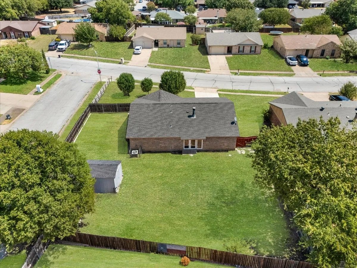 Expansive backyard featuring a manicured lawn, wood-tone fencing, and mature trees