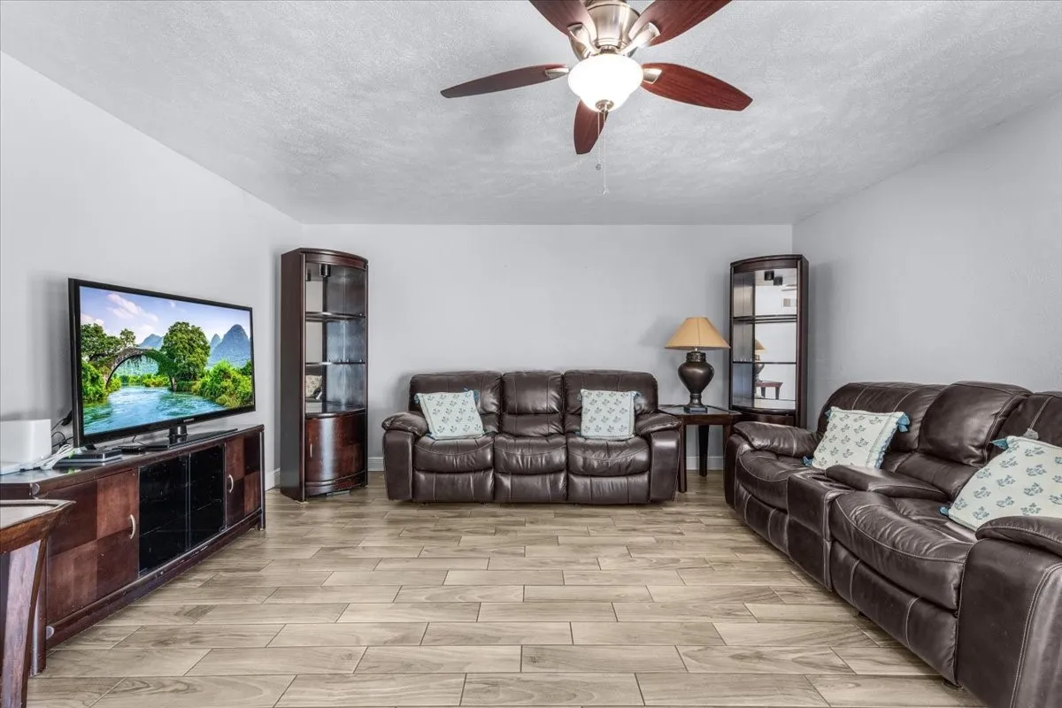 Wood-finish flooring throughout, ceiling fan with integrated lighting, and neutral wall tones