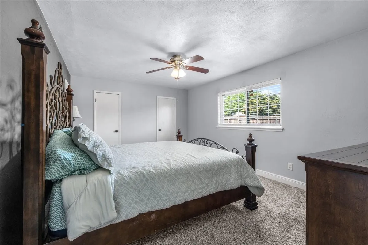 Wall-to-wall carpeting, a ceiling fan with integrated lighting, and a window with horizontal blinds