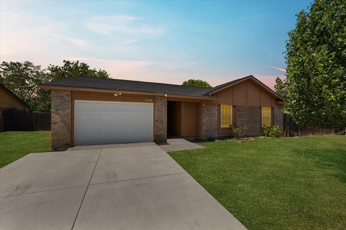 Brick and siding exterior with a dark shingle roof, attached garage, and concrete driveway