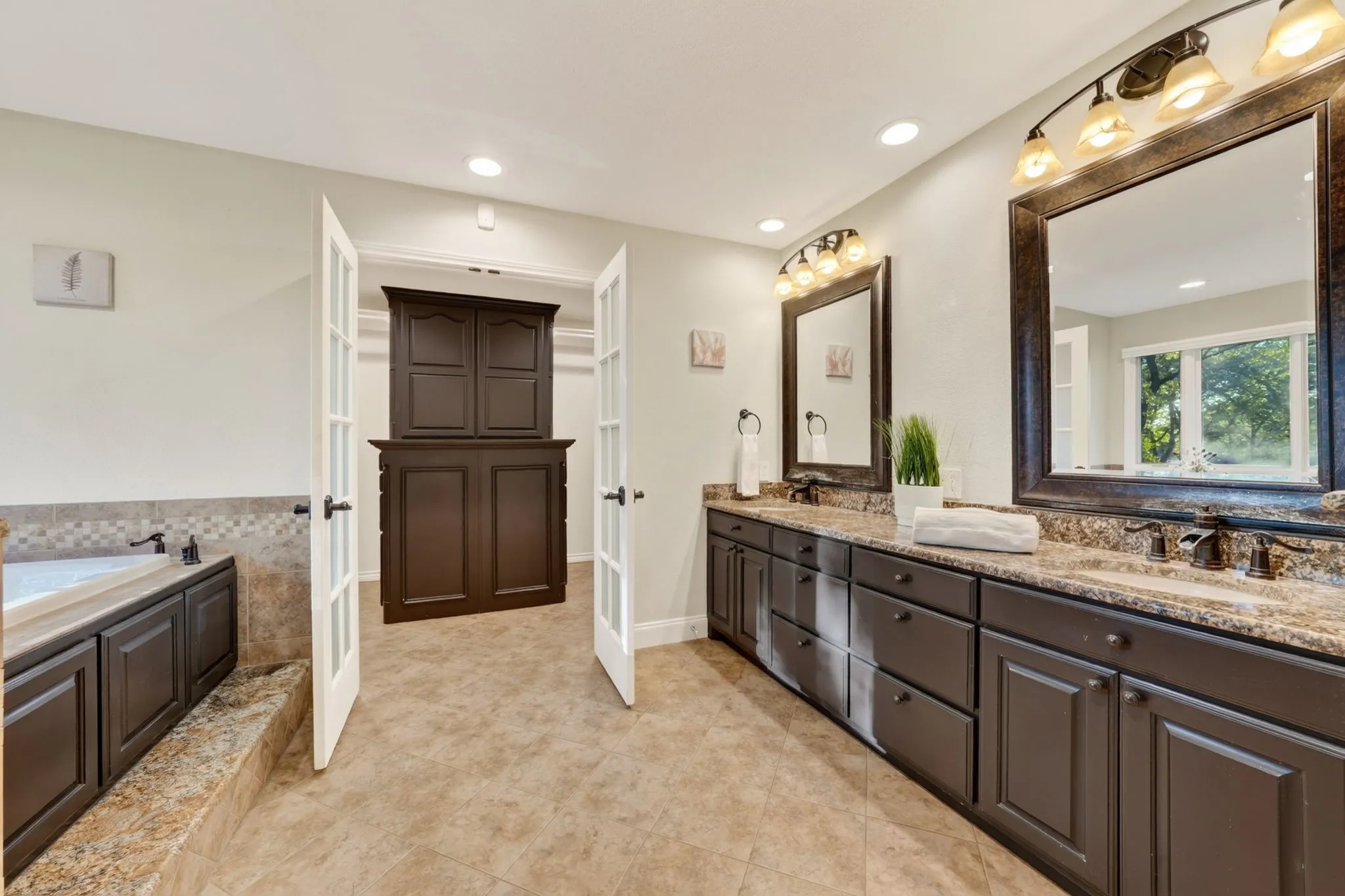 Dual vanity with dark wood cabinetry and integrated sinks, large framed mirrors, and tile flooring