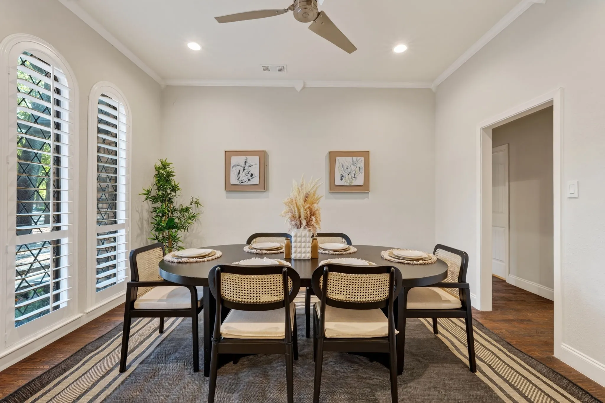 Recessed lighting, crown molding, arched windows with plantation shutters, wood flooring, and a ceiling fan