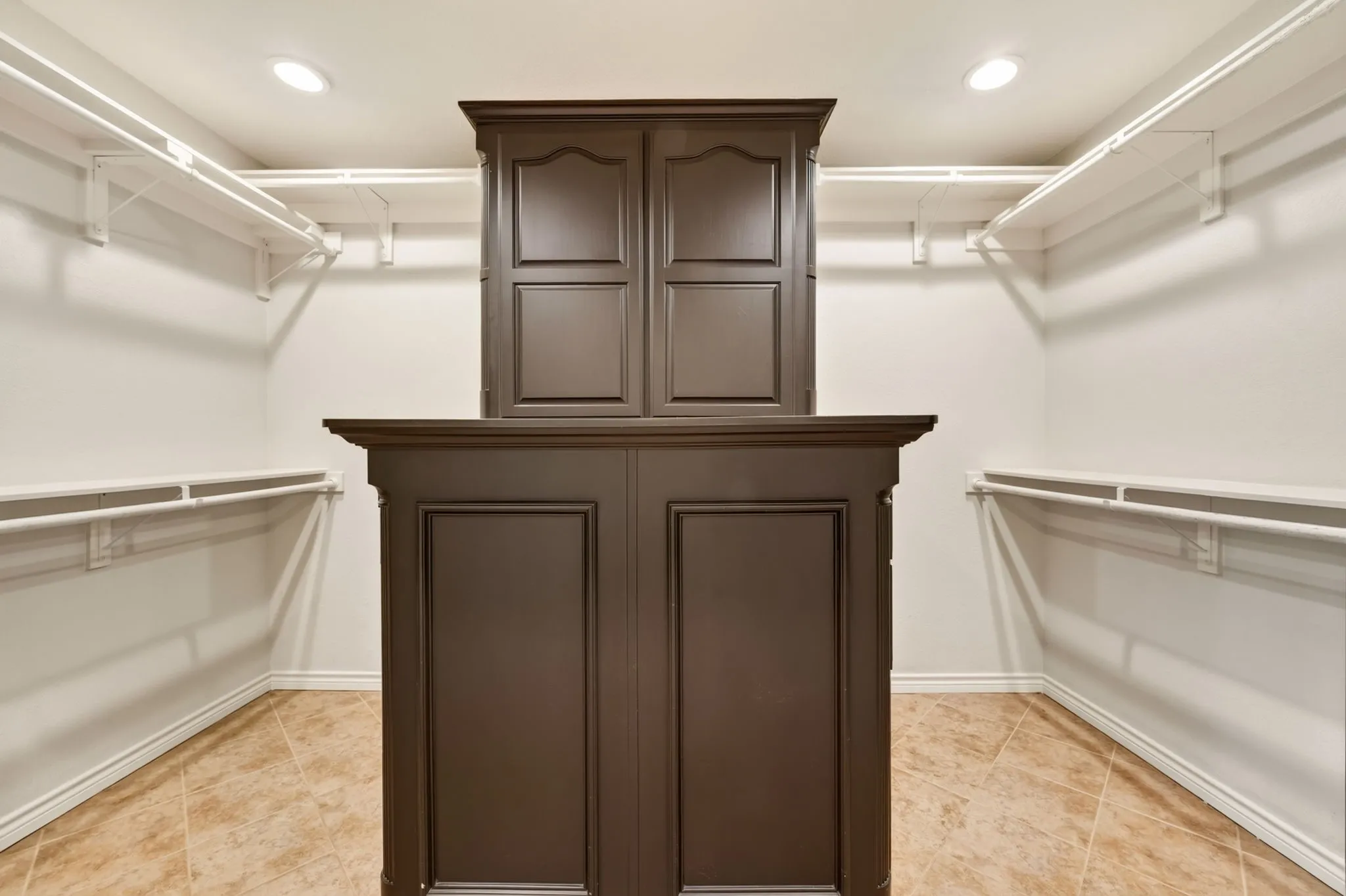Expansive Primary closet with a central wood-finish storage island featuring paneled doors