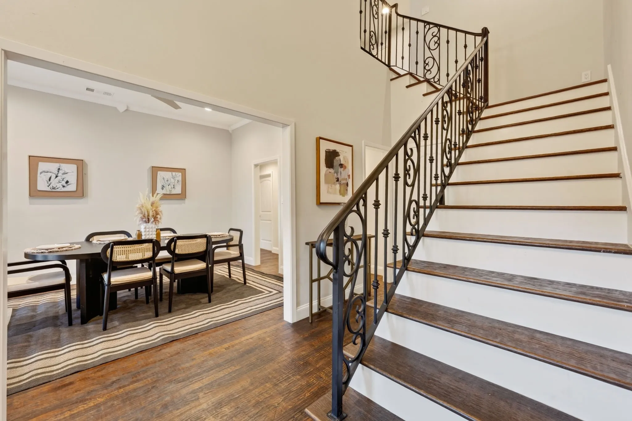 Hardwood flooring throughout, wrought iron staircase, recessed lighting, and a defined dining area