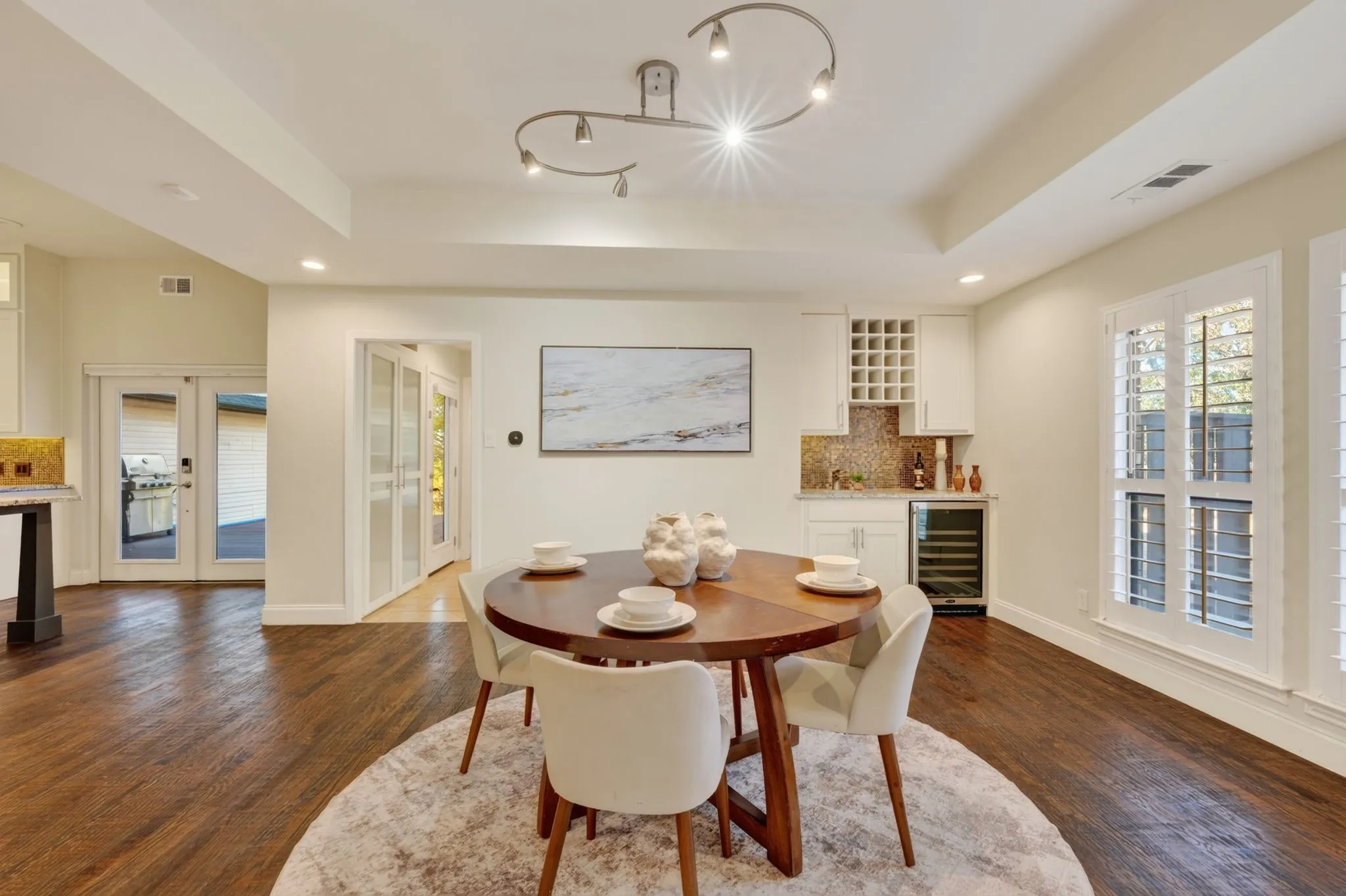 Wood-finish flooring throughout, featuring a wet bar with integrated wine storage, under-counter beverage refrigeration, and a tiled backsplash