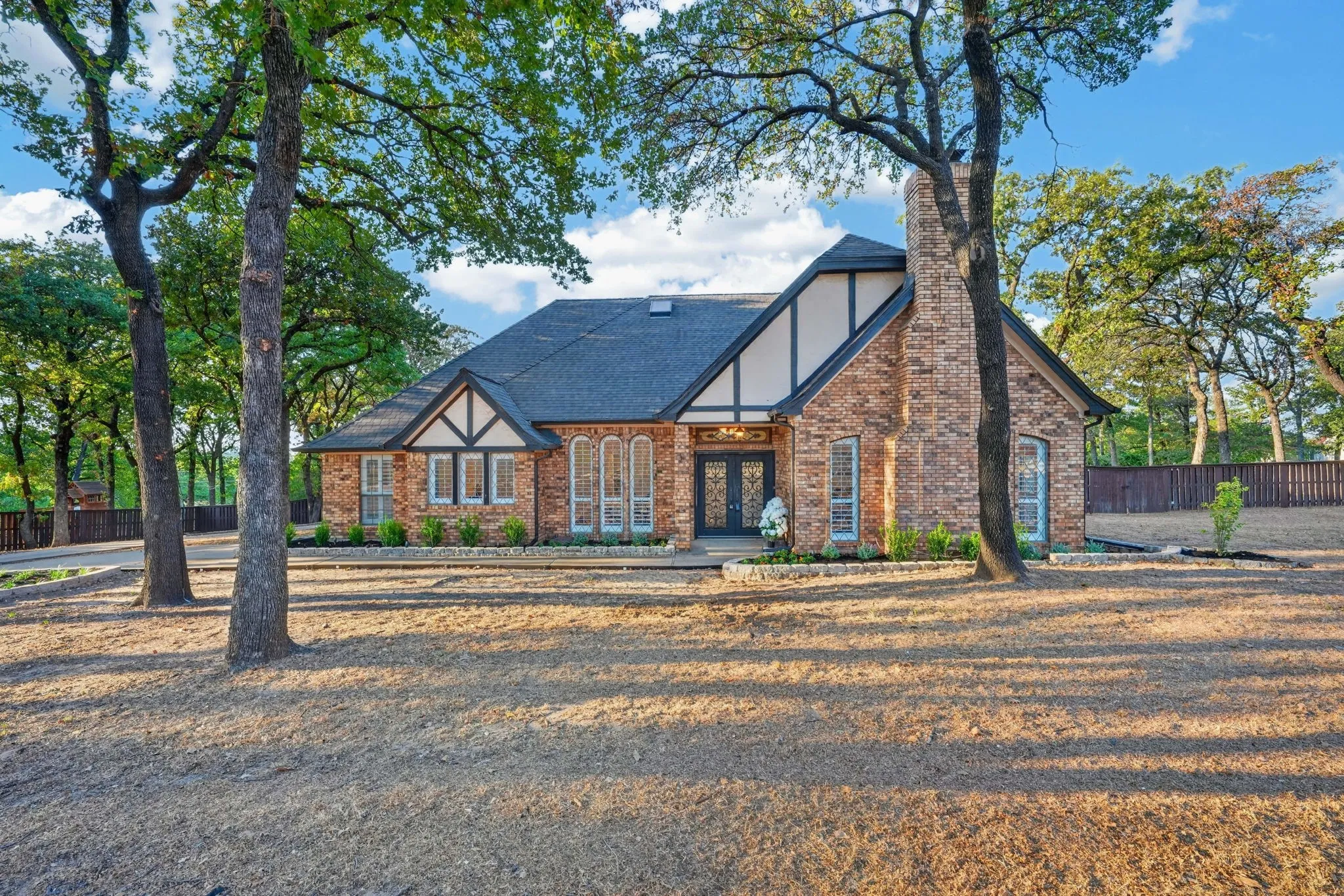 Brick exterior with Tudor-style gables and dark trim accents. Freshly landscaped with mulch and shrubs