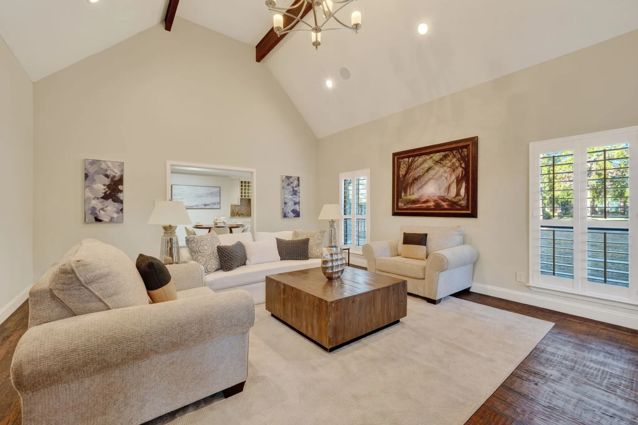 Vaulted ceilings with exposed wood beams, recessed lighting, chandelier, wood-finish flooring, and plantation shutters