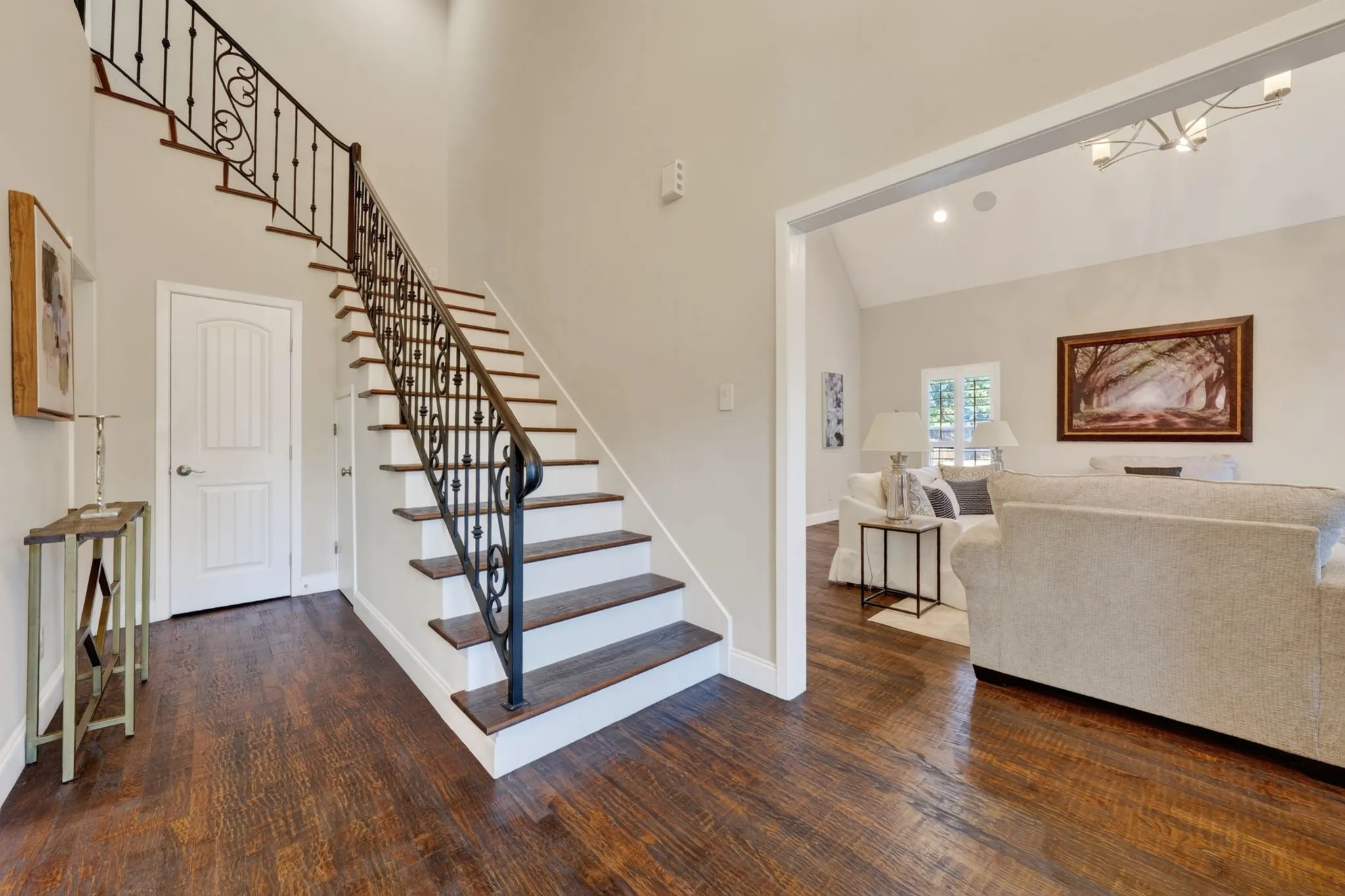 Wood flooring throughout, featuring a staircase with wrought iron balusters and risers