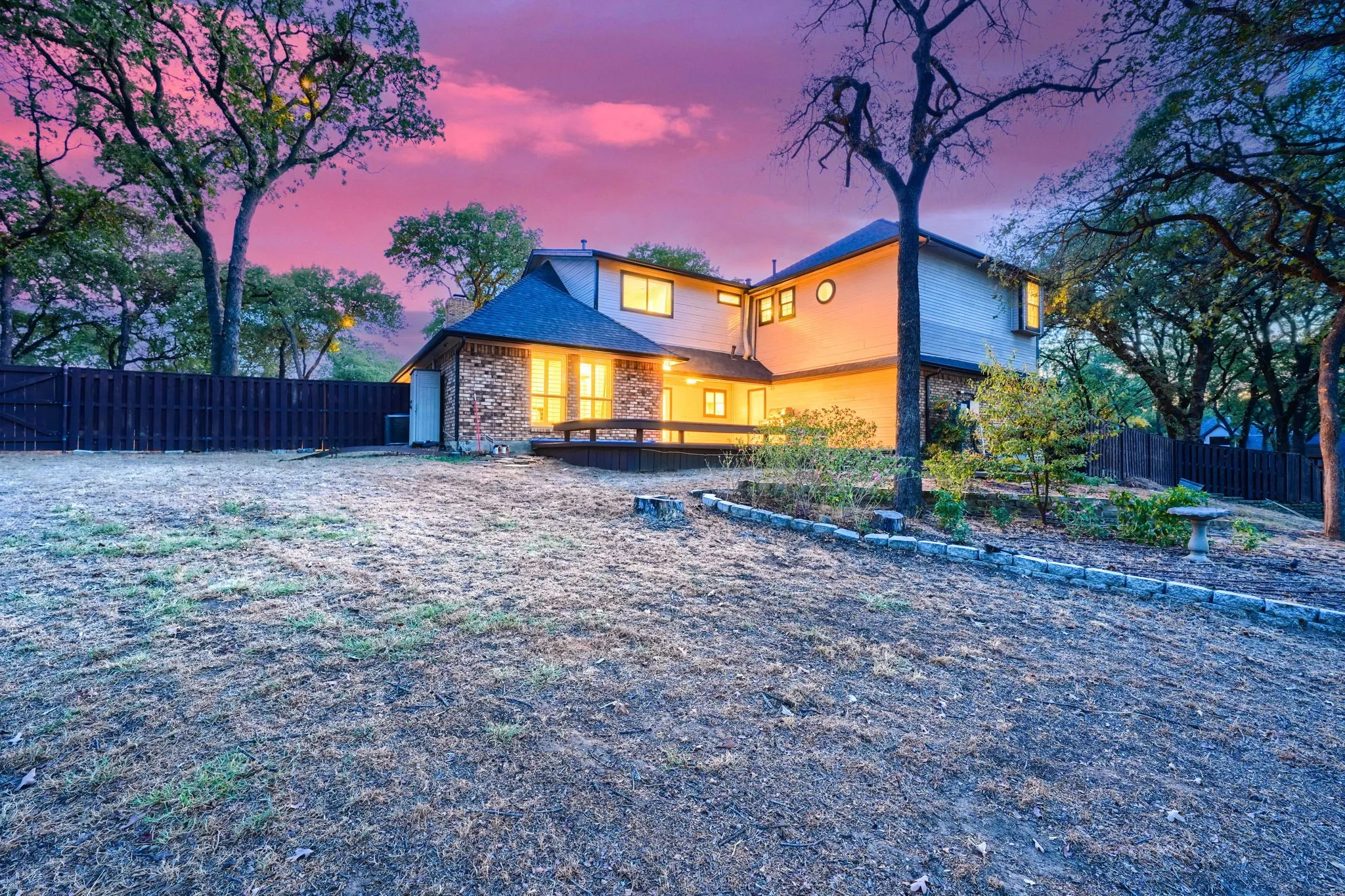 Multi-level exterior with stone and siding facade, private wooden deck, and mature trees