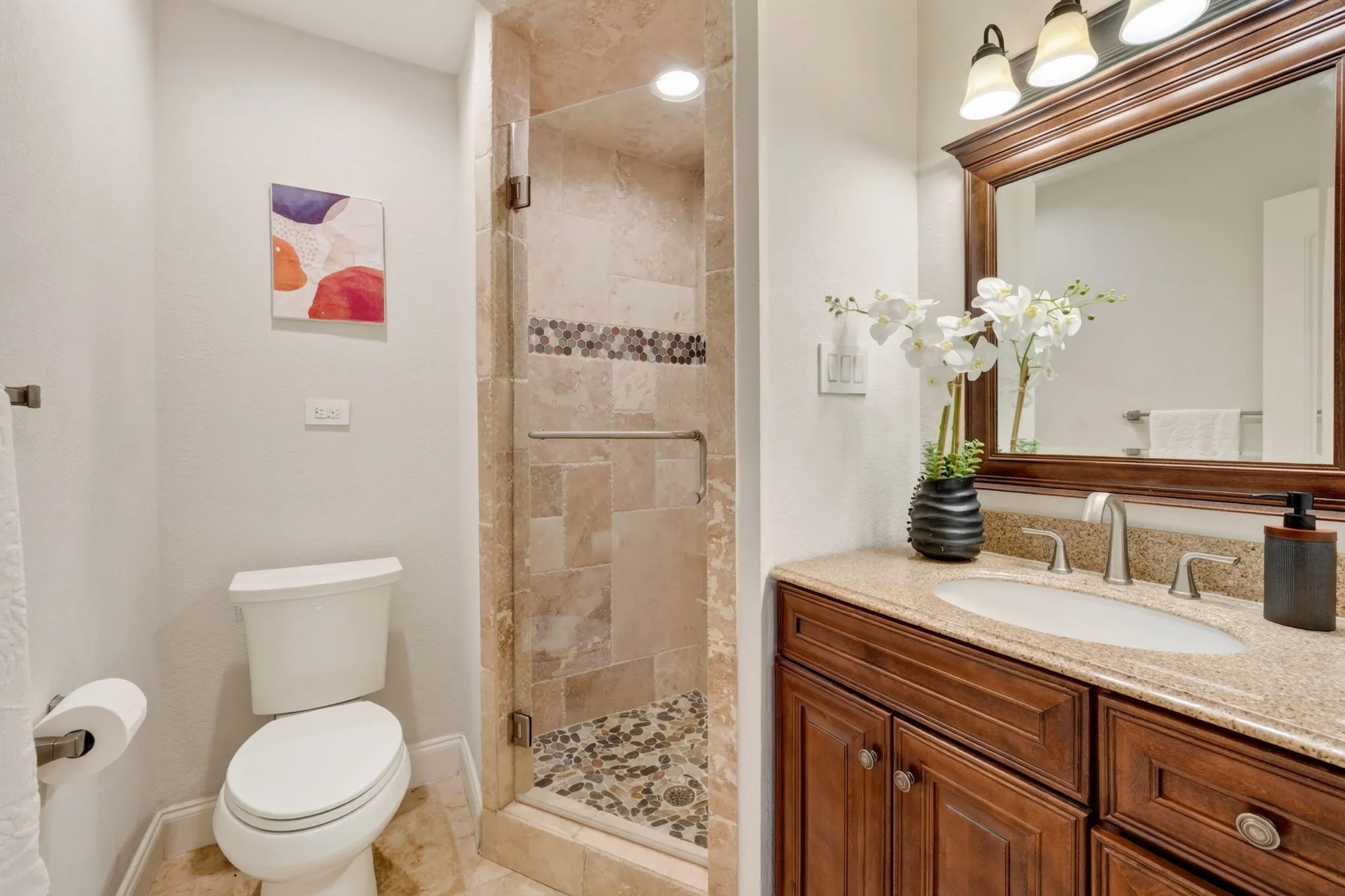 Downstairs Bathroom with Step-in shower with natural stone tile surround, glass enclosure, and pebble floor