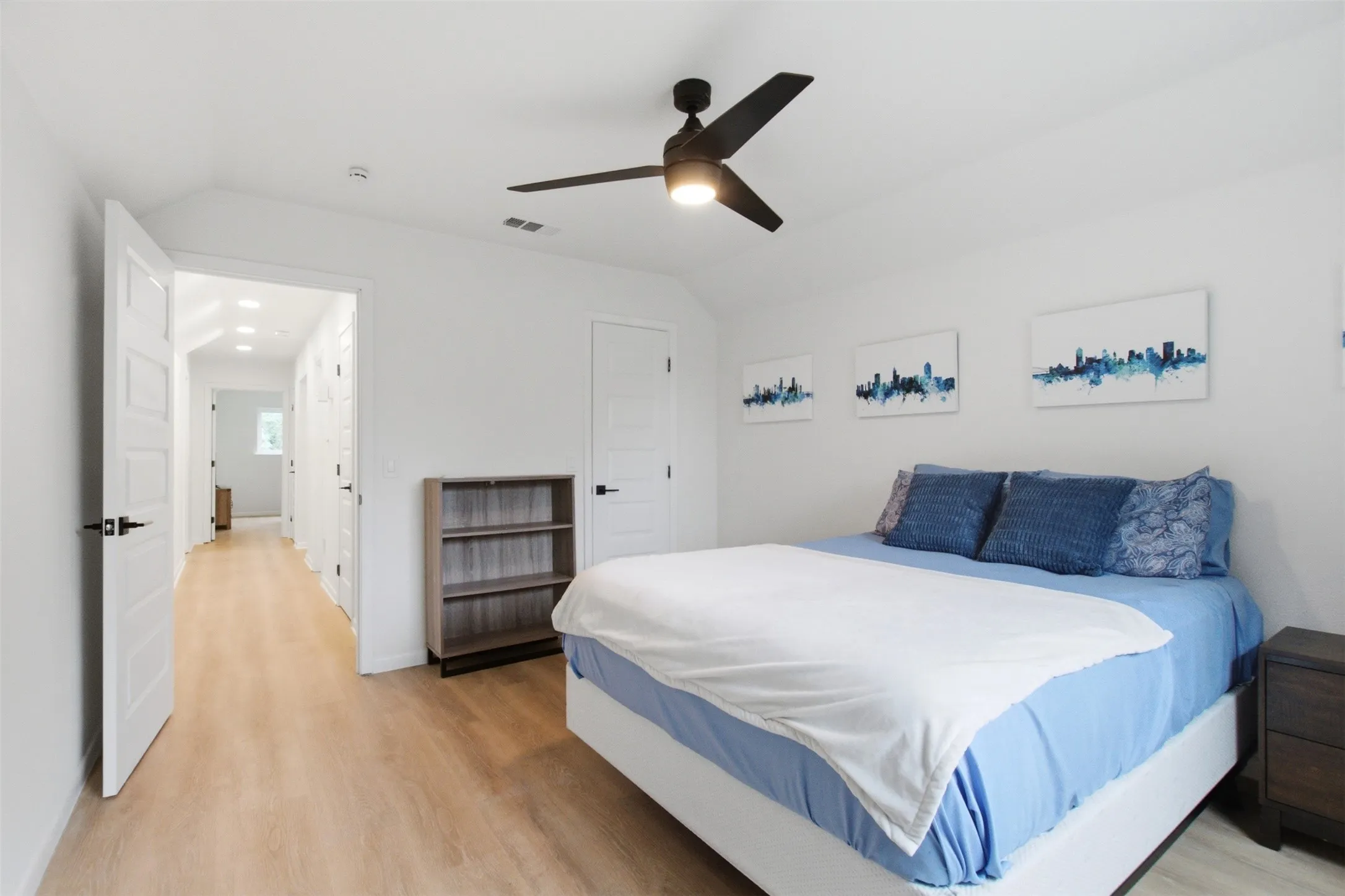 Spacious room featuring wood-finish flooring, a contemporary ceiling fan with integrated lighting, and crisp white walls