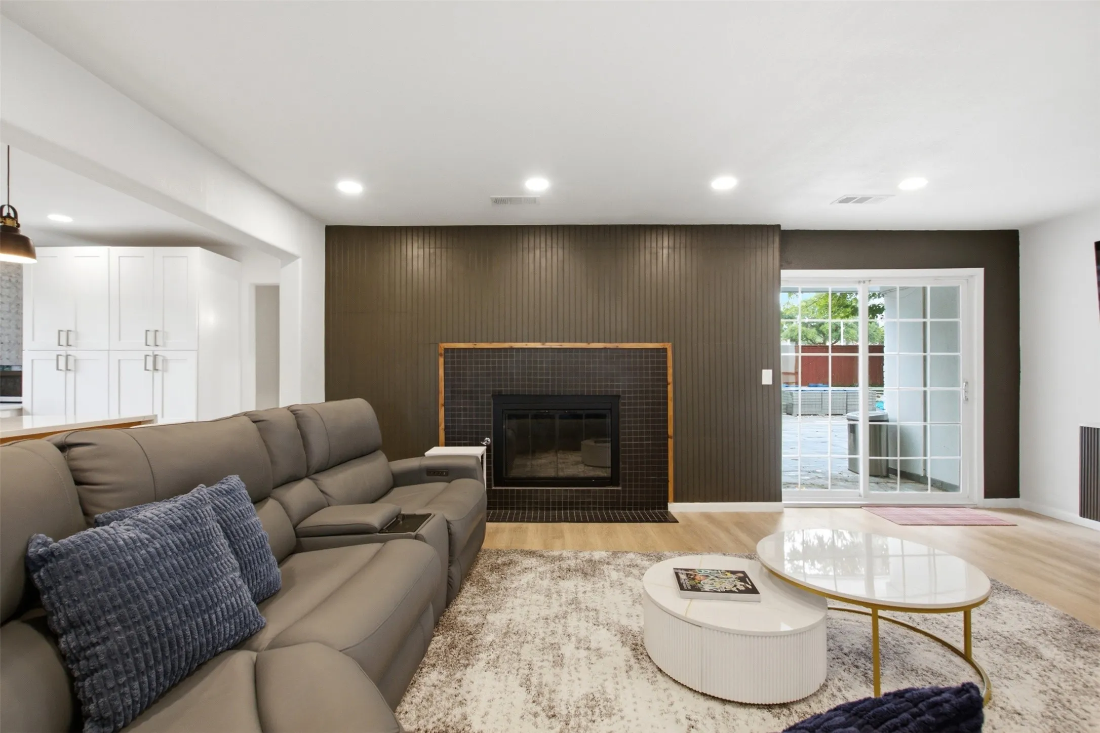 Living area featuring wood-finish flooring, recessed lighting, and a dark accent wall with a built-in fireplace