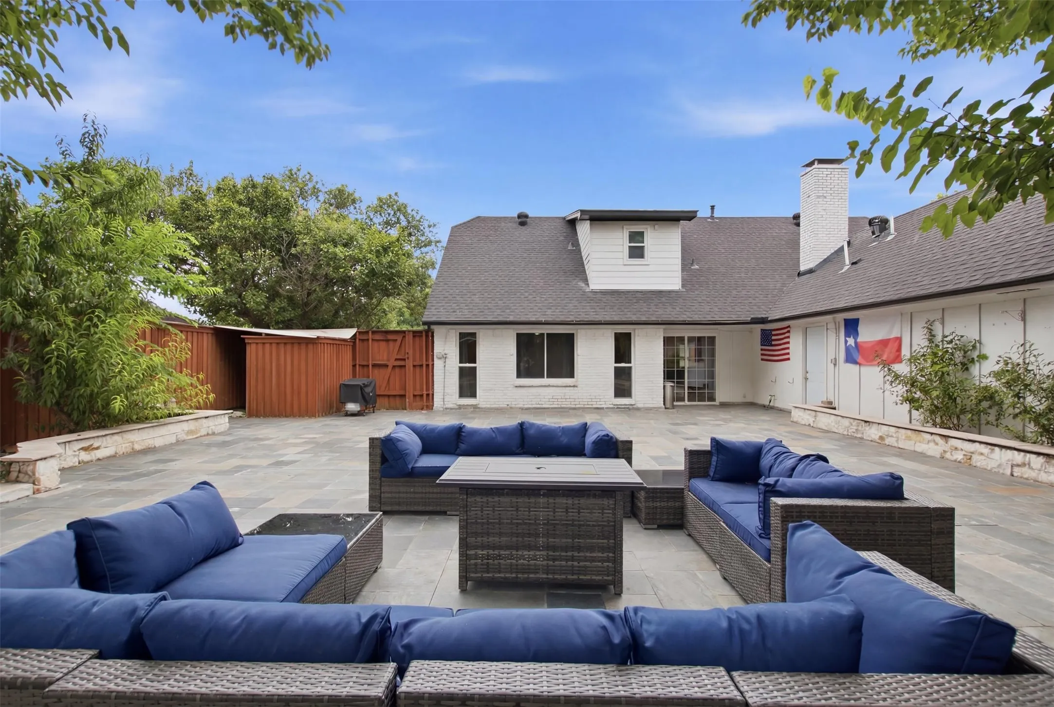 Expansive outdoor patio featuring large format pavers, a private perimeter fence, and direct access to the interior via a sliding glass door