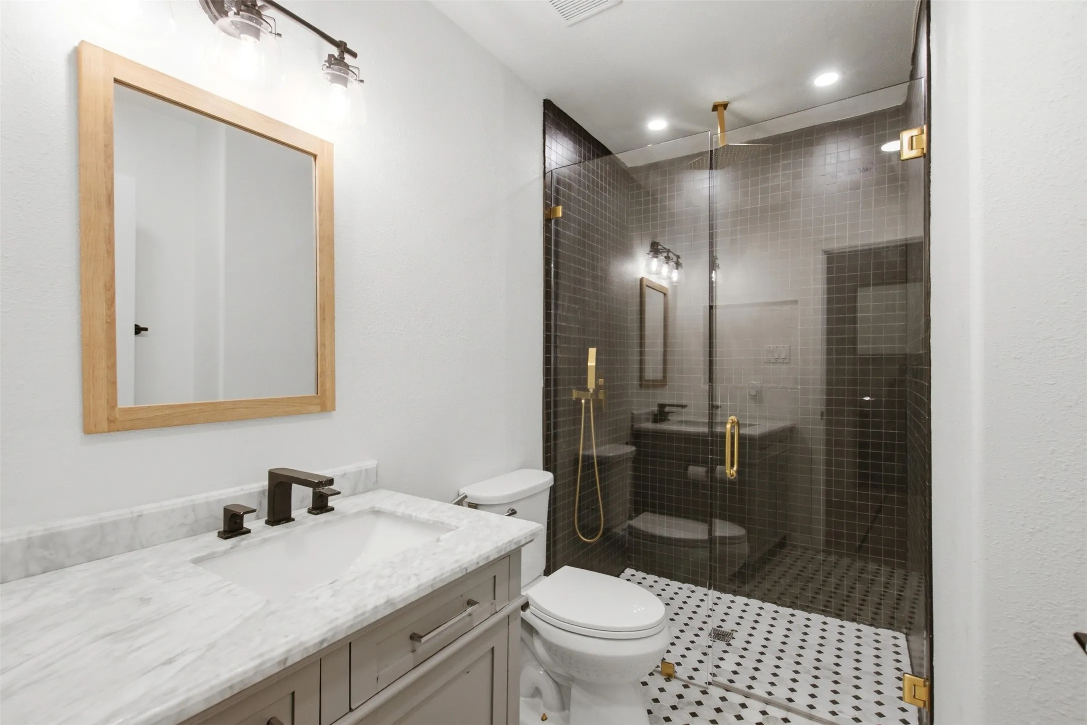 Bathroom featuring a single vanity with a white countertop and rectangular sink, dark bronze fixtures, and a natural wood-framed mirror