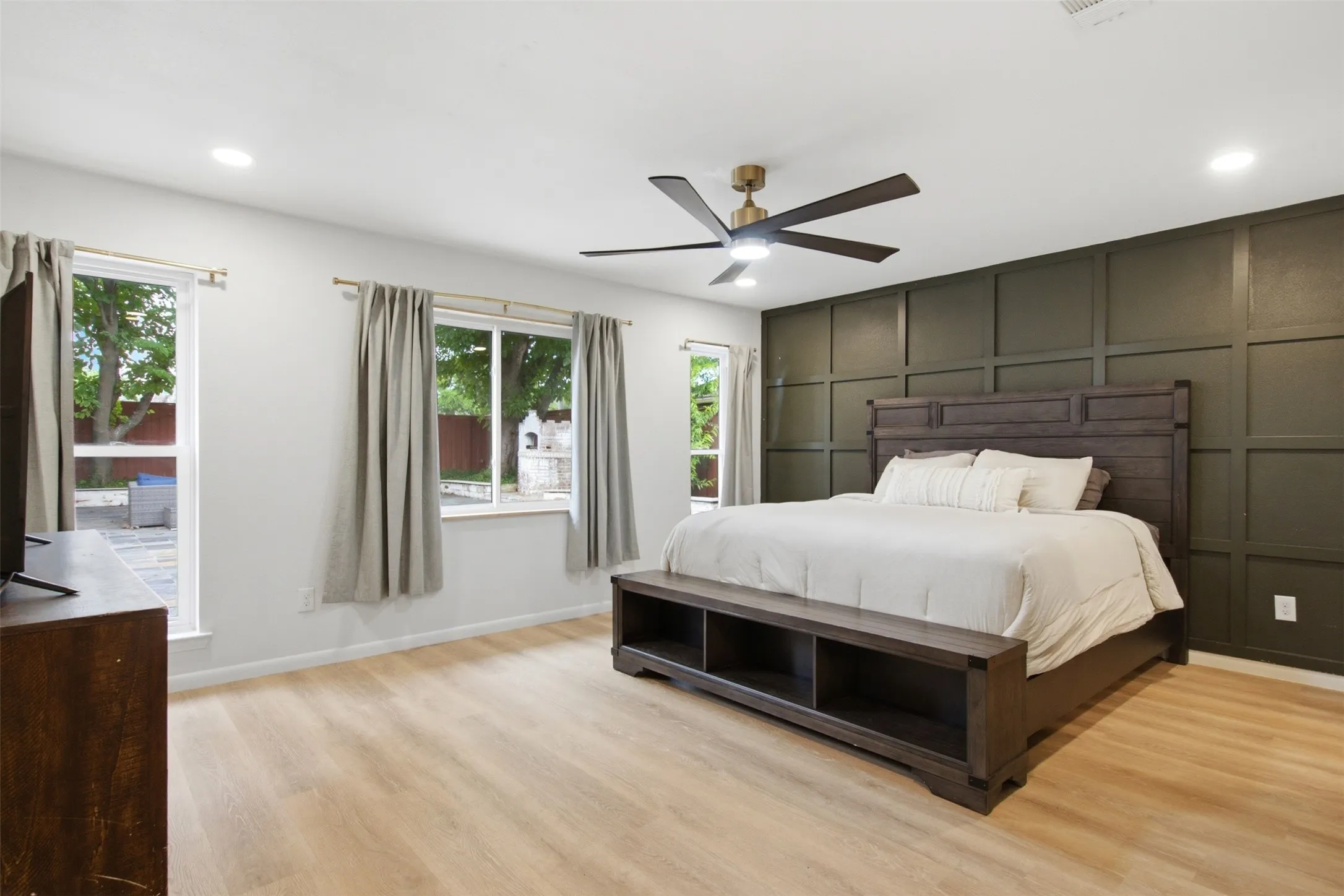 Spacious room featuring light wood-finish flooring and a decorative accent wall with panel molding