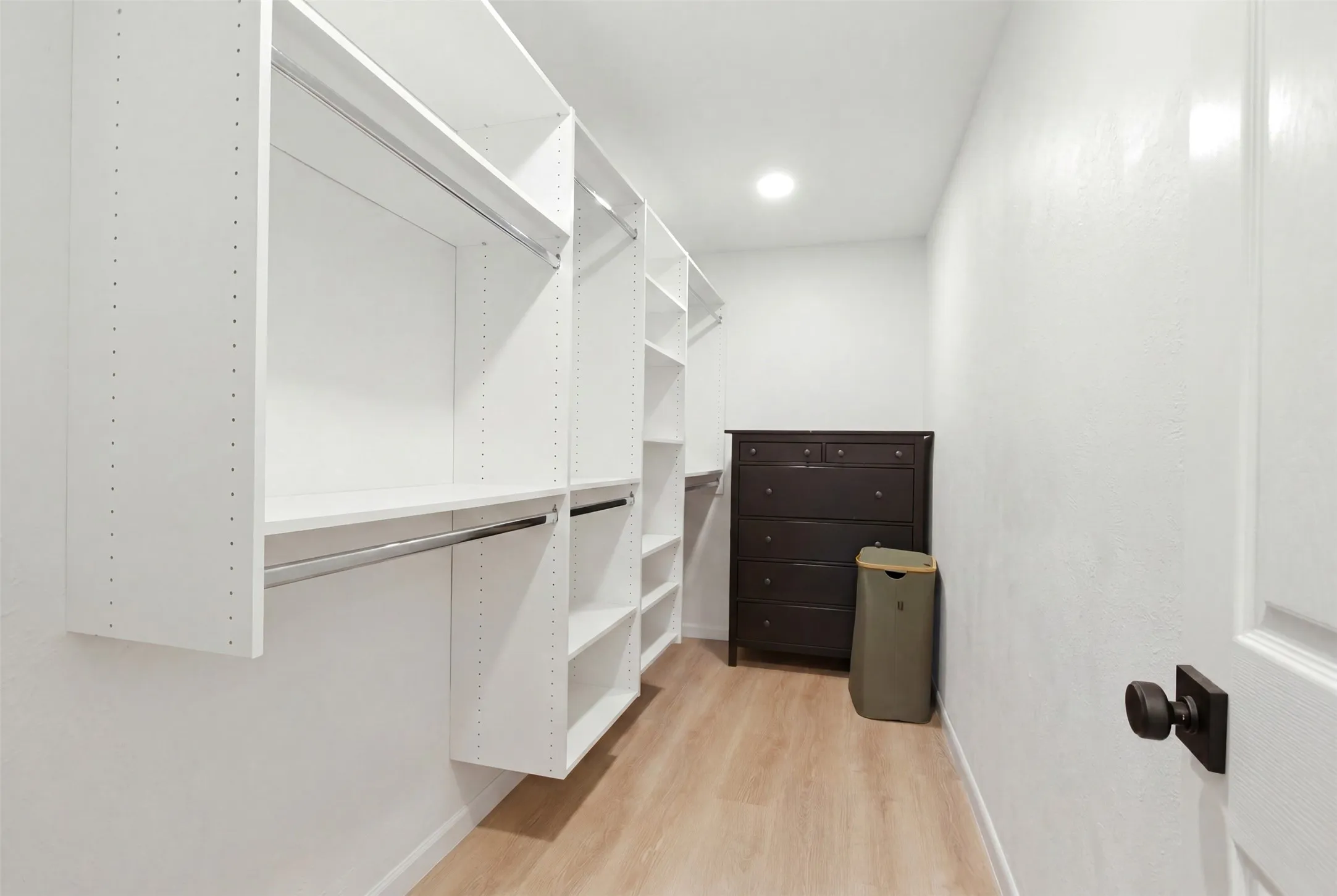Custom closet system featuring white shelving and chrome hanging rods