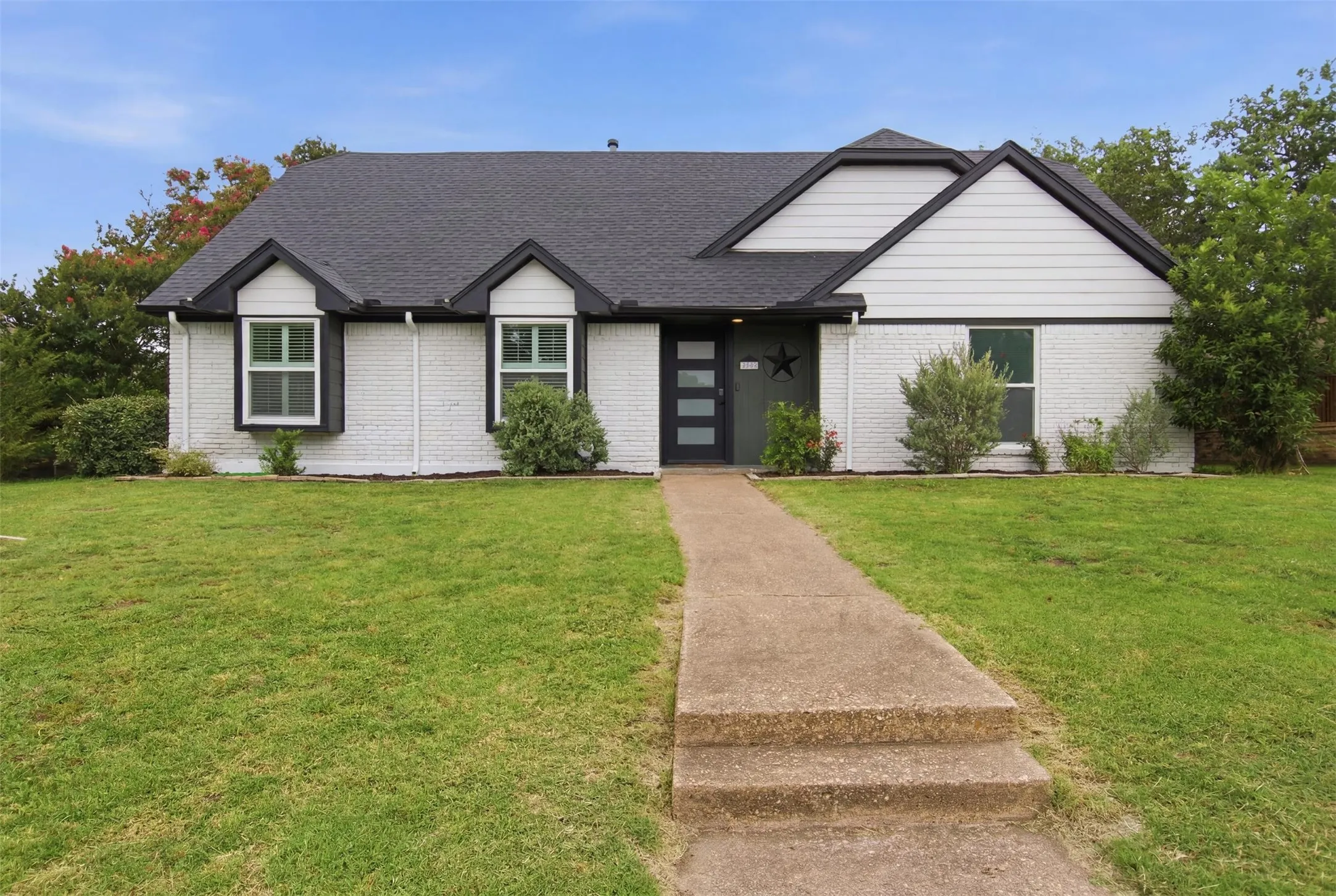 White brick exterior featuring a dark asphalt shingle roof