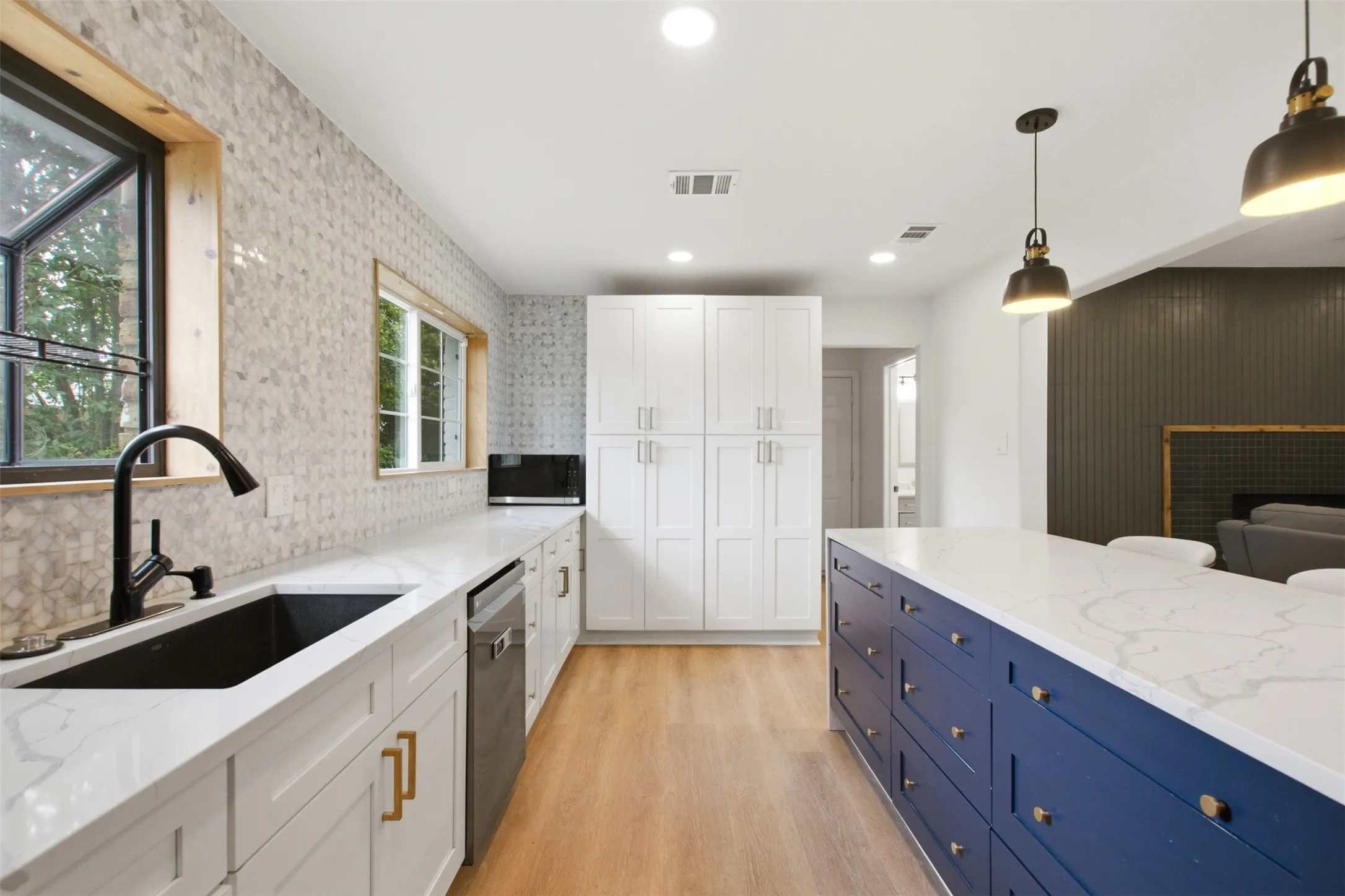 Kitchen featuring a blue island with a quartz countertop, white cabinetry, a black sink with a matte black faucet, and patterned tile backsplash