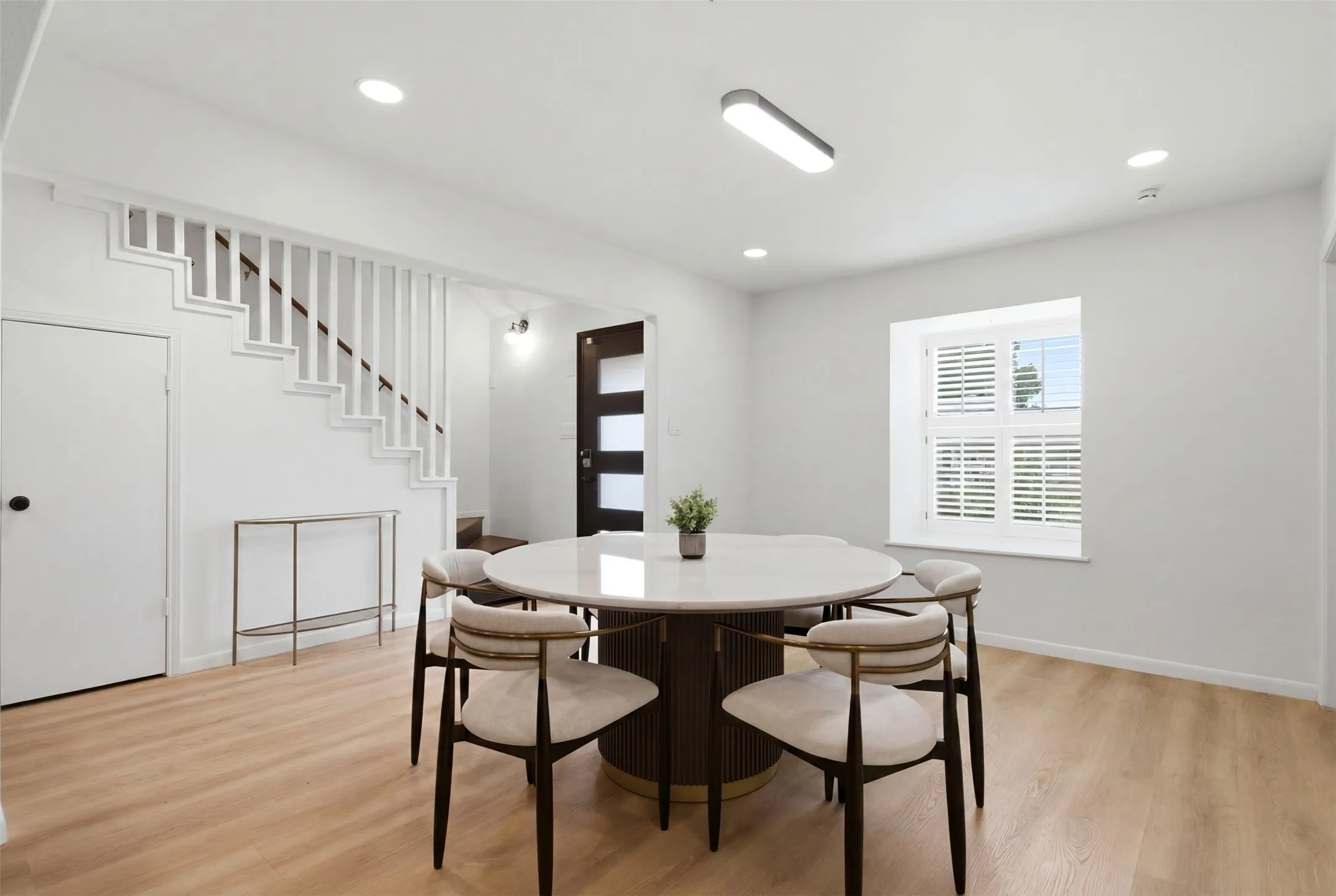 Open-concept room featuring light wood-finish flooring and a white painted staircase with vertical balusters