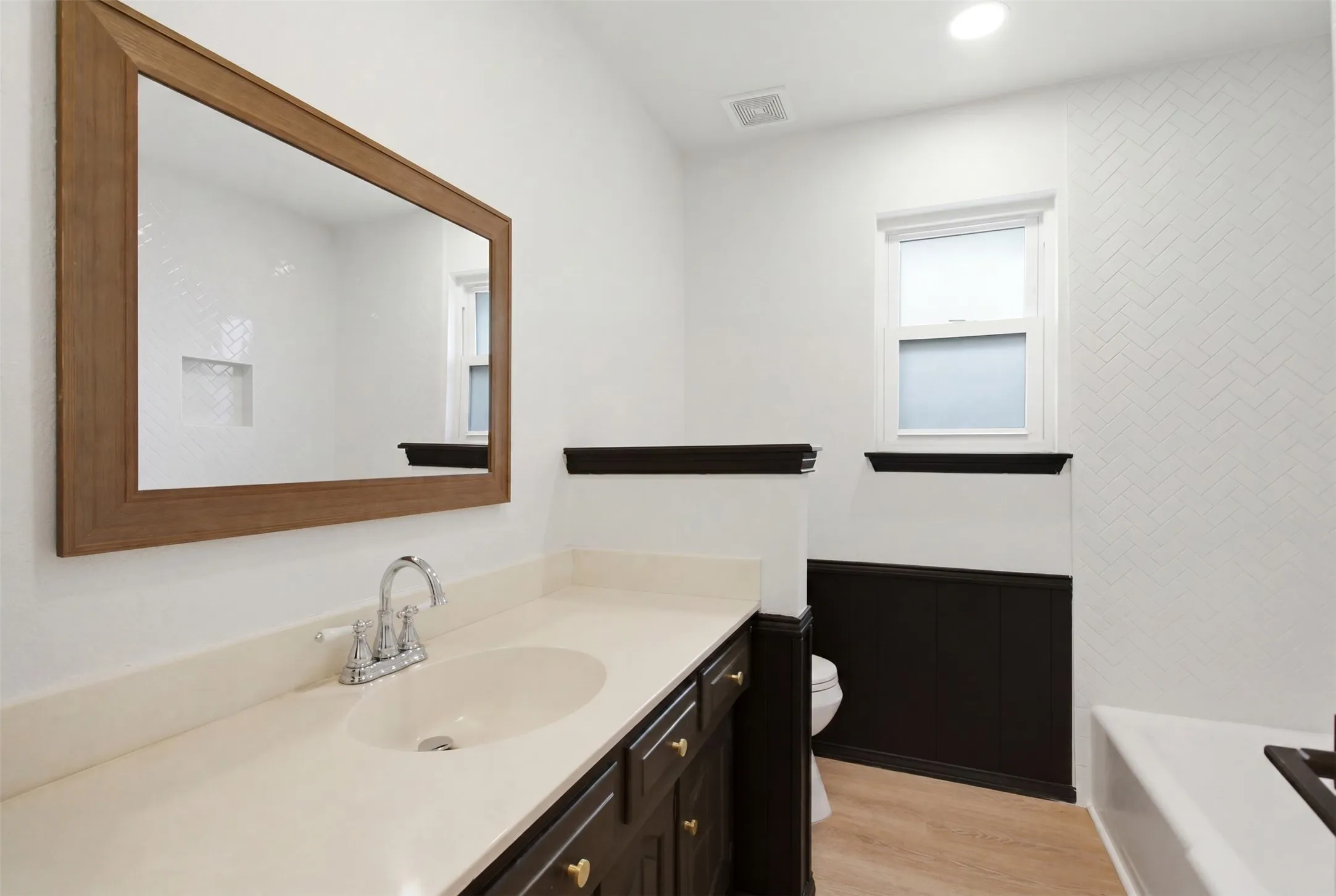 Bathroom featuring a single vanity with a light-toned countertop and an undermount sink