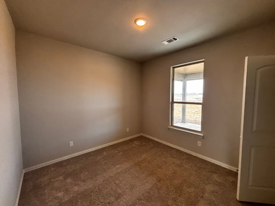 Neutral wall paint, plush carpet flooring, recessed ceiling lighting, and a window with exterior visibility
