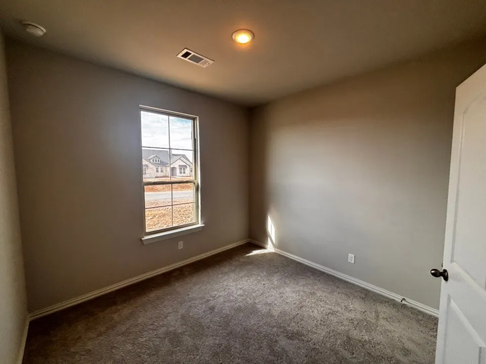 Neutral wall finishes, recessed ceiling lighting, and dark carpet flooring
