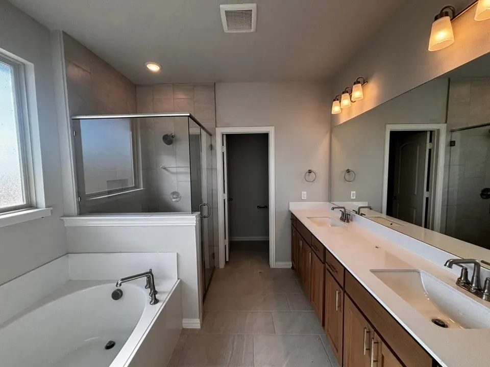 Dual vanity with undermount sinks, wood-finish cabinetry, and expansive mirror