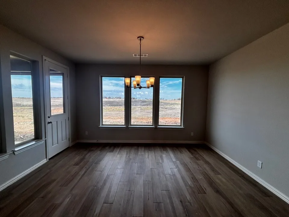 Expansive interior with wood-finish flooring and a contemporary chandelier