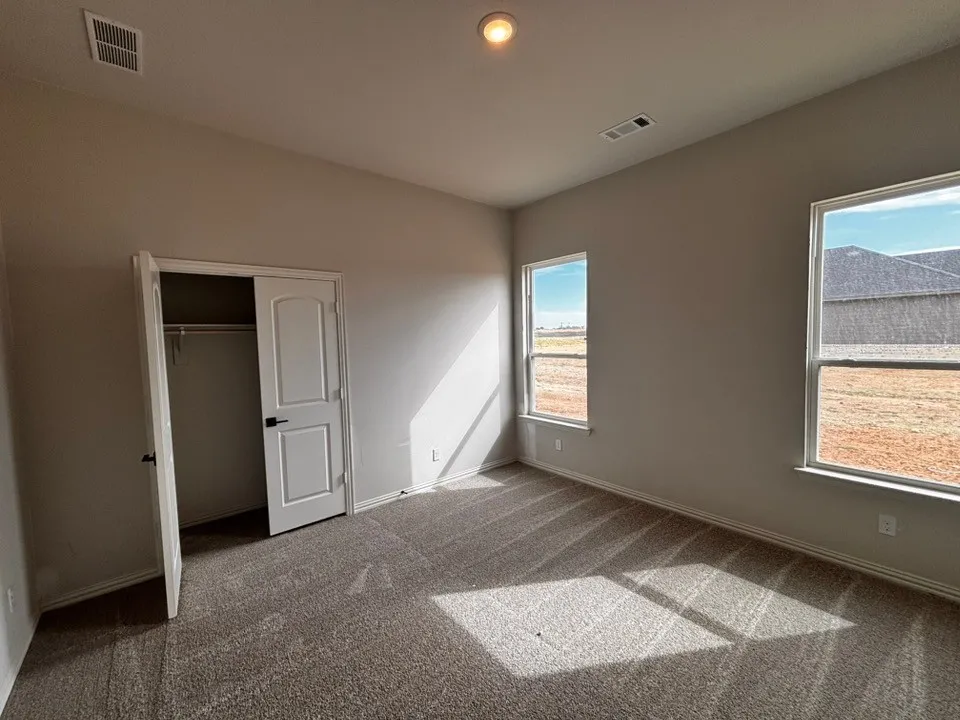 Carpeted flooring, two windows, recessed lighting, and a bi-fold closet door