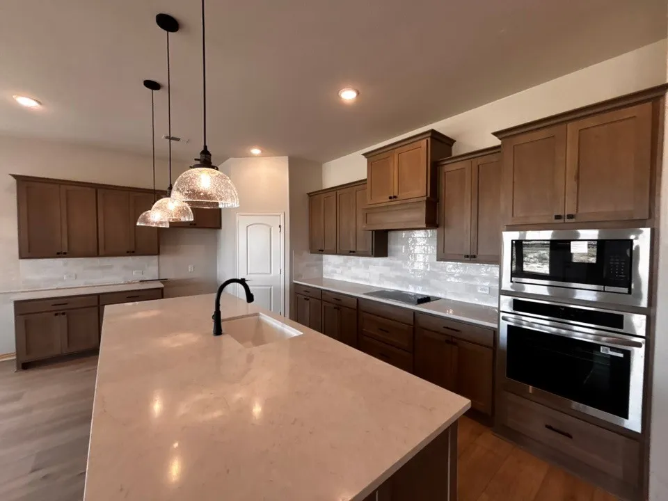 Kitchen featuring wood-finish cabinetry, light-toned countertops, and a white tile backsplash